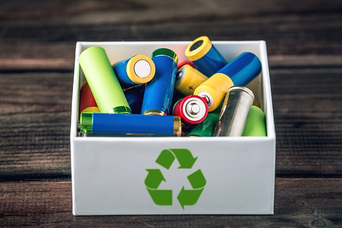 Used AA and proper disposal of toxic to the environment and soil batteries on a blue background. The concept of technologies of processing of harmful and recycling substances for ecological